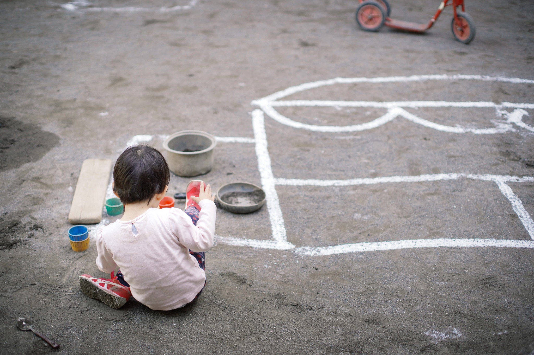 園庭で遊びに夢中になる子どもの後ろ姿